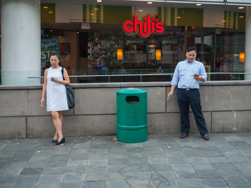 Dos personas fuman tabaco en la calle.