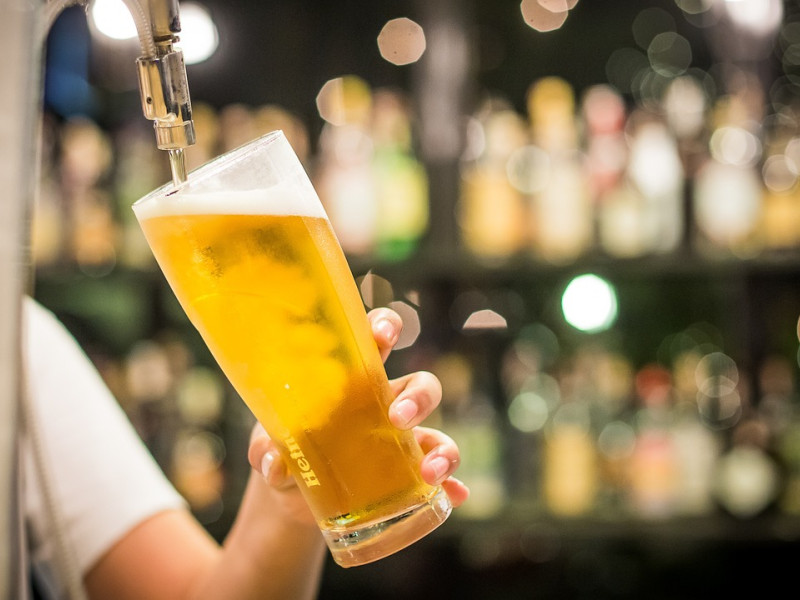 Un camarero sirve una caña de cerveza en un bar