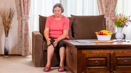 Mujer mayor que sufre de dolor de rodilla en casa